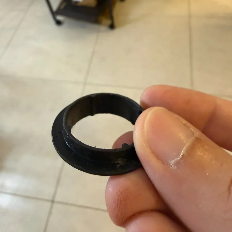 Foto real: anel preto impresso em 3D segurado entre os dedos